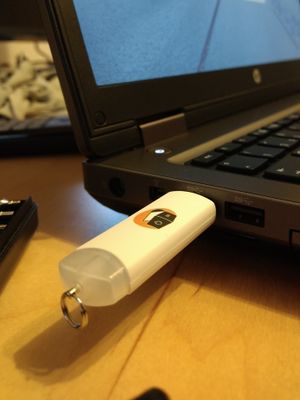 Ein USB-Stick, auf dessen Oberseite das „Computertruhe“-Logo gedruckt wurde, steckt in einer USB-Buchse eines Laptops.